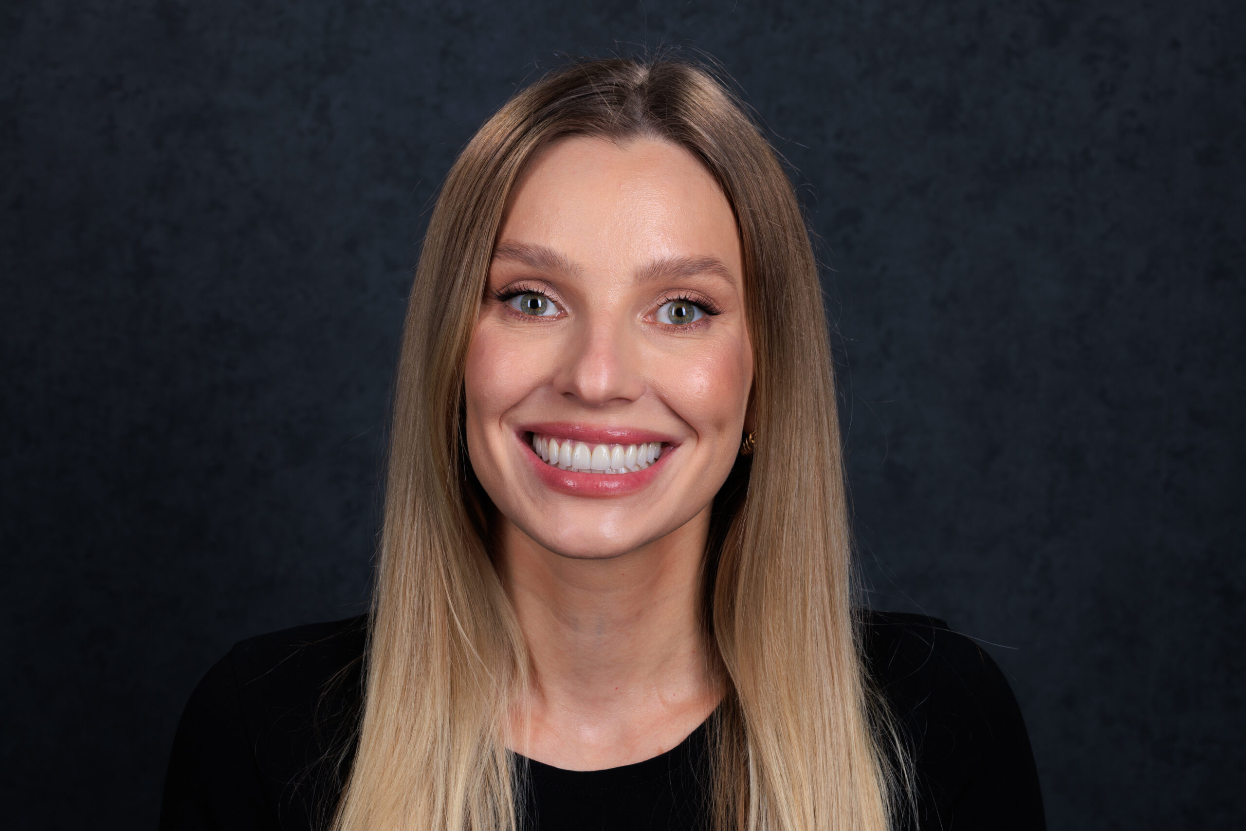 Smiling portrait against a charcoal backdrop